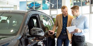 Why your ego is sabotaging your sales and how to stop it young affable consultant talking about features of new car to customer. business man listen to him, choosing new auto in dealership